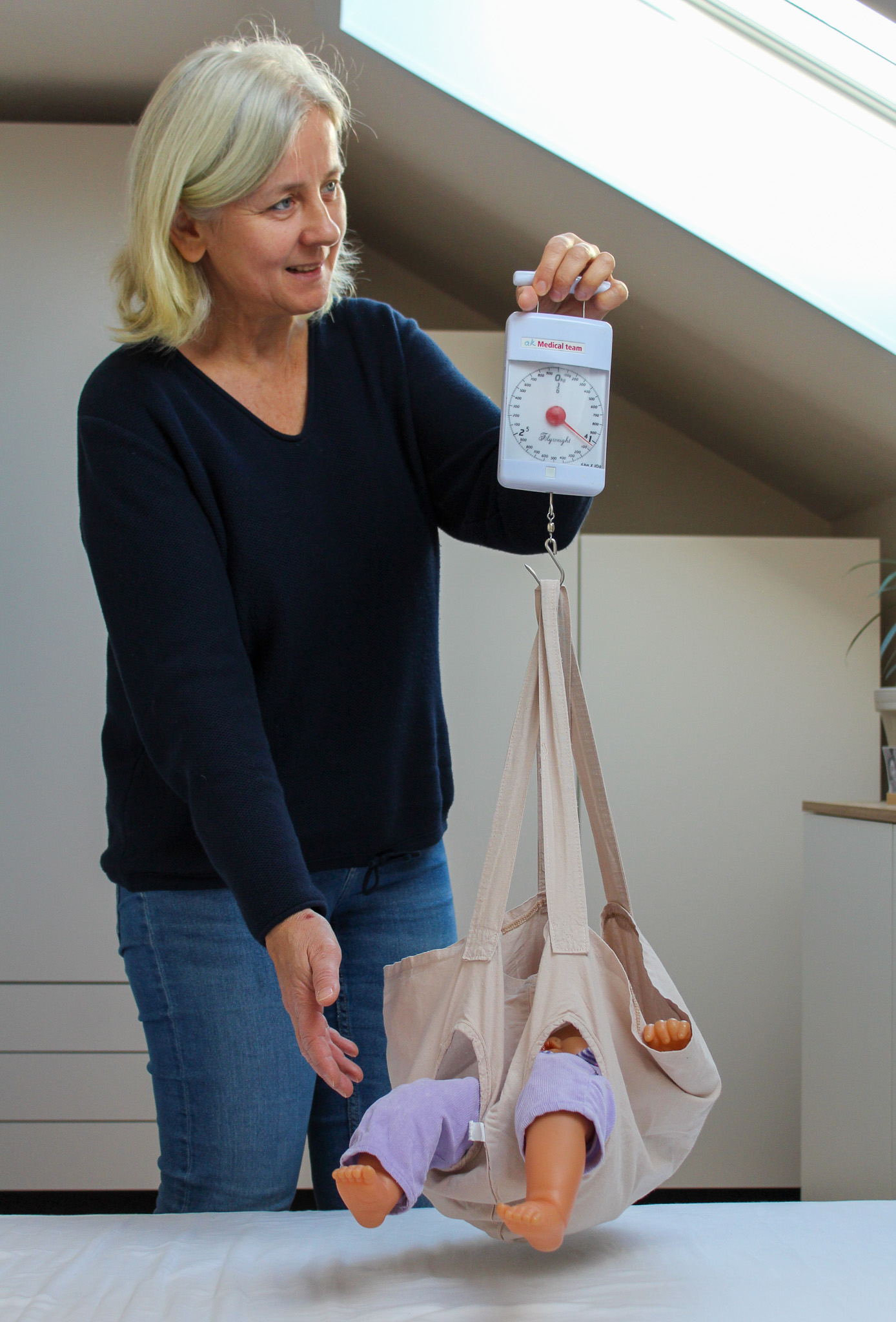 Hebamme Irena wiegt ein Baby bei einem Hausbesuch